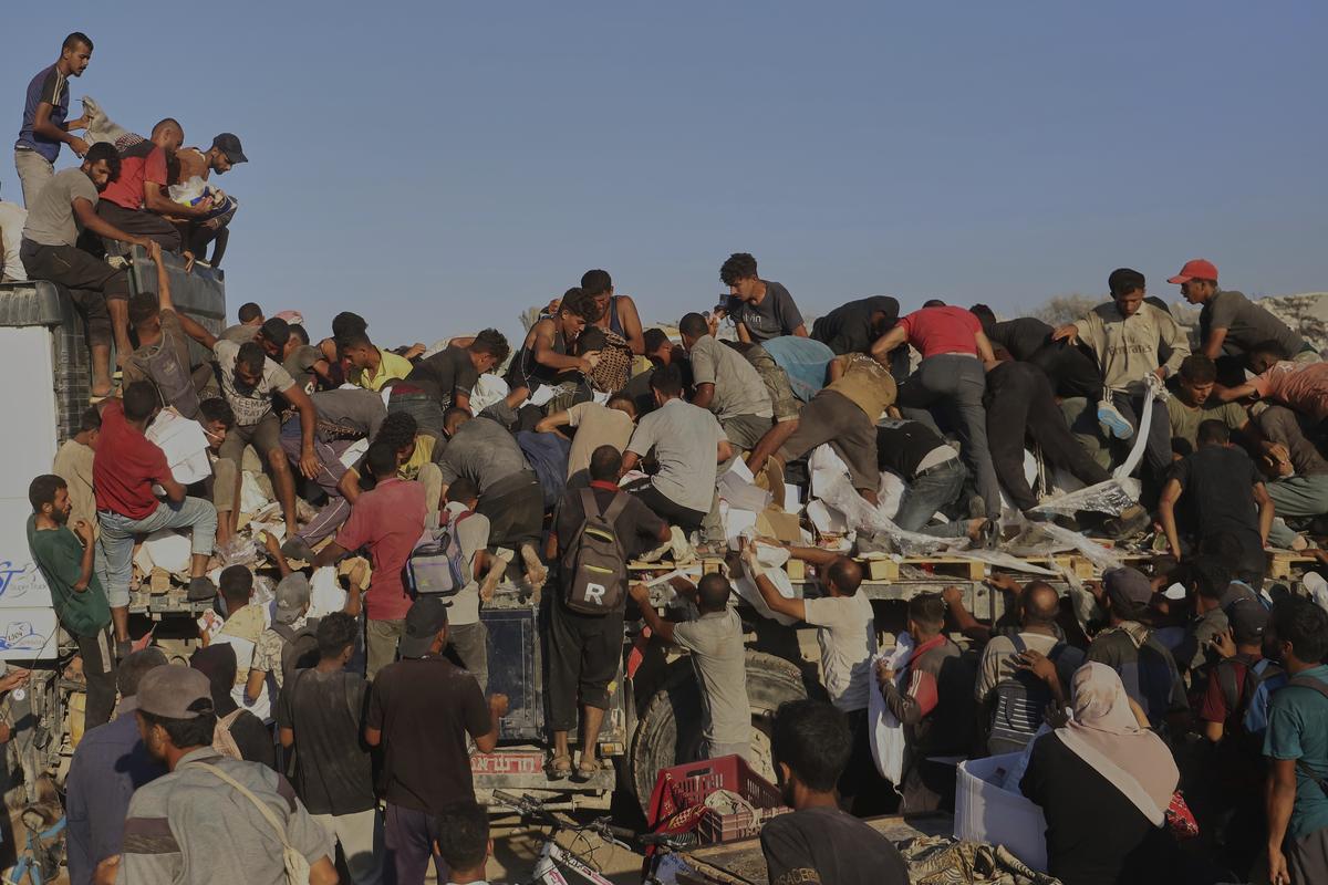 Watch: Palestinians scramble on aid trucks for food and supplies